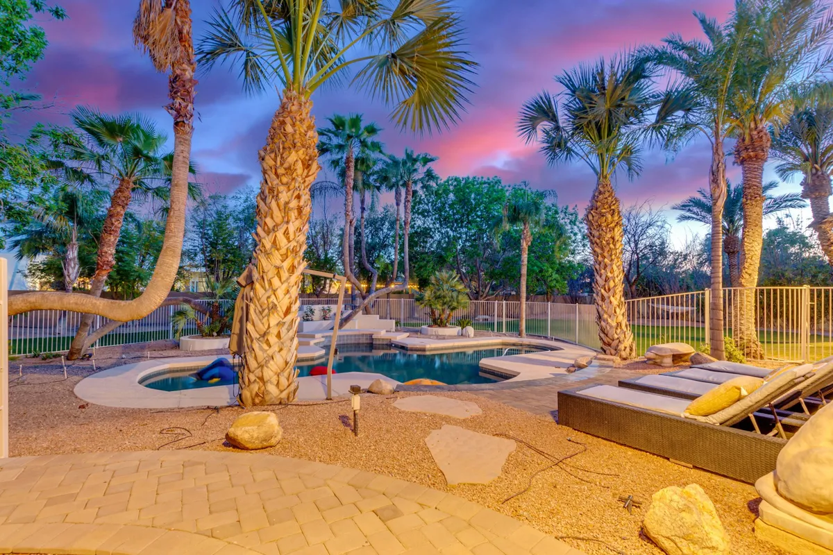 A sparkling swimming pool with surrounding palm trees and outdoor lounge chairs creates a serene and festive setting. The pool is ready for both daytime fun and evening relaxation, with plenty of space for group activities and socializing.
