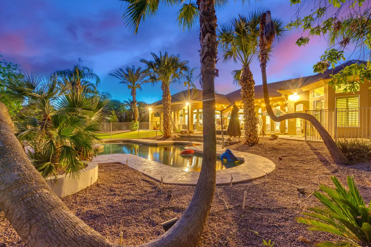 A serene evening view of the pool area, with palm trees and elegant exterior lighting creating a welcoming ambiance. The tranquil mood hints at sunset swims, stargazing, and quiet morning coffee by the water—the types of experiences the section describes as part of a relaxing getaway, no matter the season.