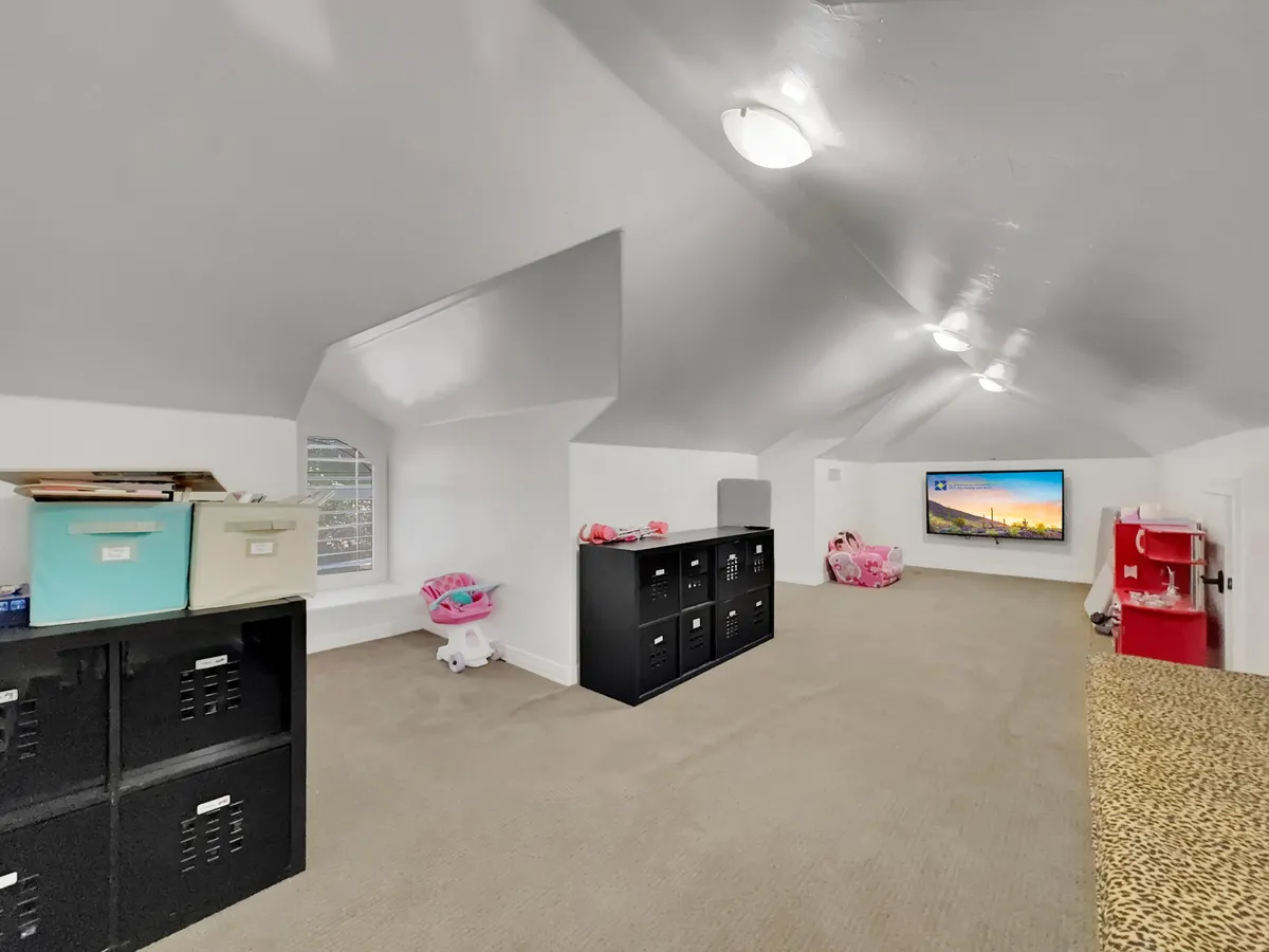This interior image features a cheerful game room setting, complete with a wall-mounted television, colorful storage boxes, a child's toy kitchen, and a family-friendly atmosphere. The space is clearly designed for play and creativity, inviting children to enjoy hours of entertainment.